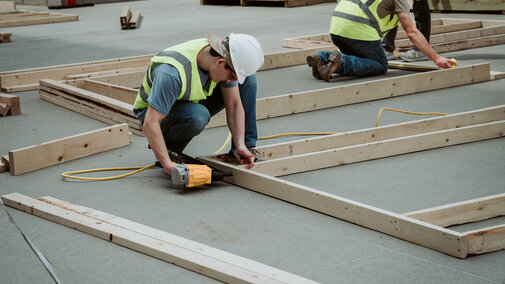 Construction workers assembling wooden frames outdoors.