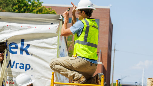 A Durham School student working outdoors on an in-progress shed.