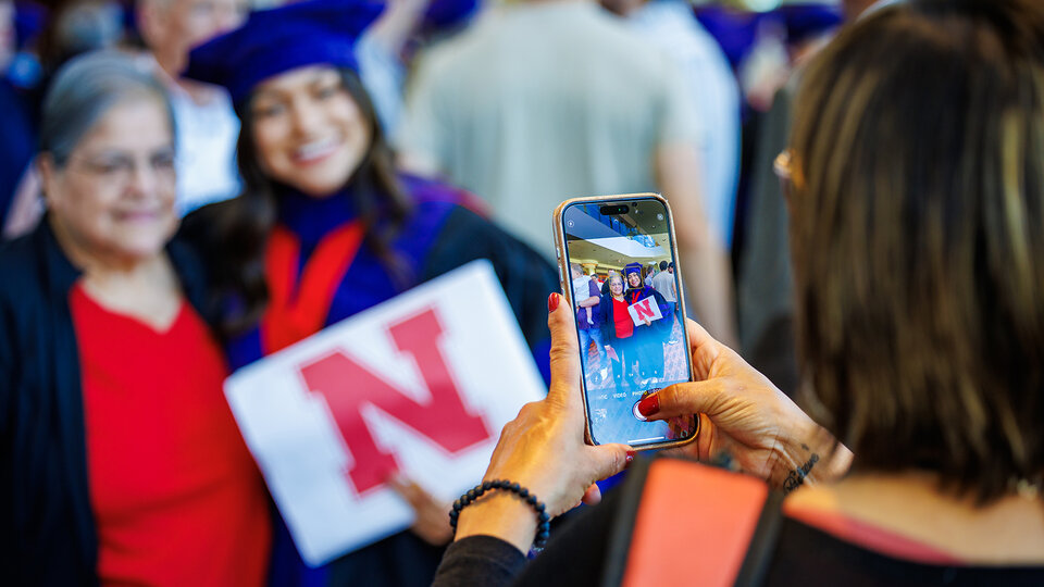 Jori Peters smiles as her photo is taken with a family member after the Nebraska Law graduation ceremony on May 3.
